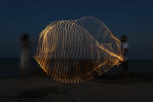 Friends swinging the light strip at night long exposure effect